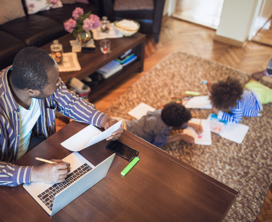 A father working at his desk while watching his children. 