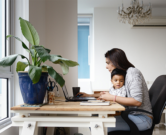 A woman working on a computer with child.