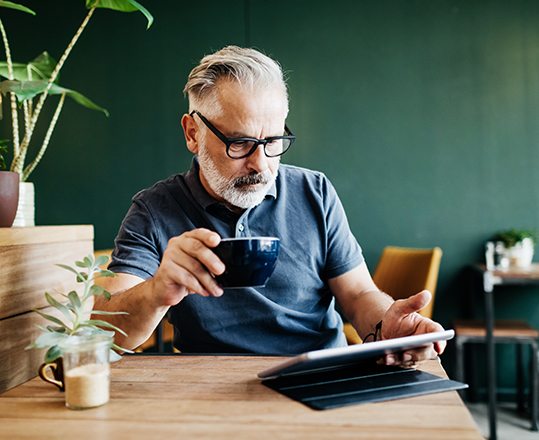 mature man working on tablet in coffee shop