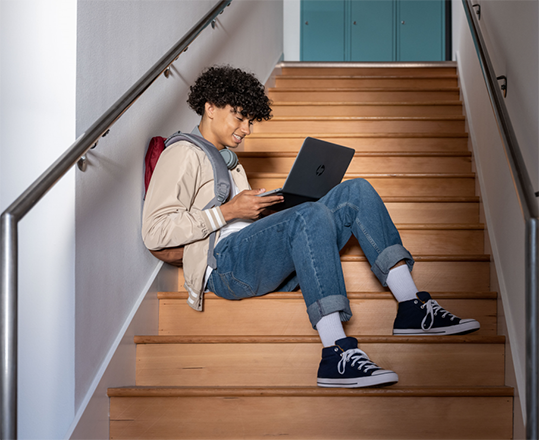Student using a laptop while sitting on a stairway.