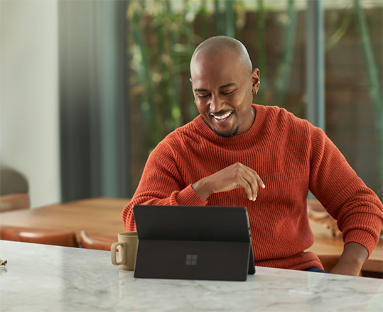 man laughing as he uses a Surface tablet in his kitchen