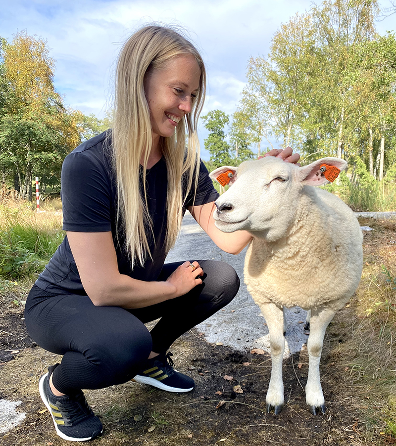 Karoliina Kettukari petting a lamb.
