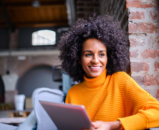 Smiling woman using a digital tablet in hip environment.